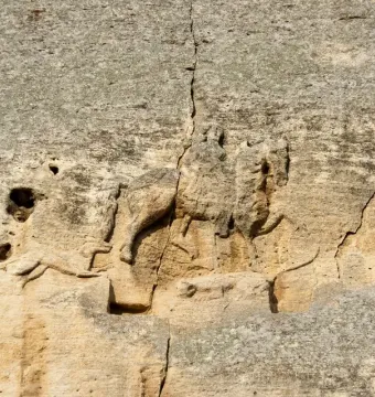 Madara Rider rock relief showing a horseman on horseback, a dog running ahead, and a faint fallen figure below.