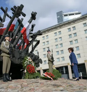 The Monument to the Fallen and Murdered in the East with crosses and Polish flags, flanked by soldiers and floral wreaths during a commemorative ceremony.