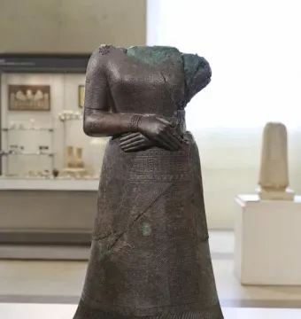 Headless statue of Napir-Asu with hands folded across the waist and a long patterned garment.