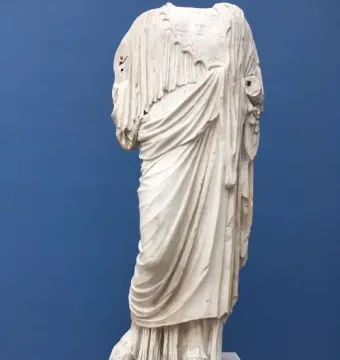 Athena Giustiniani marble statue shown as a headless, armless torso with flowing robes and a circular emblem on the chest.
