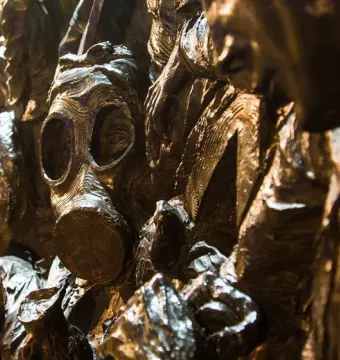 Bronze relief sculpture detail on the Battle of Britain Monument, showing a gas mask among textured figures.