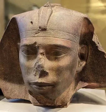 Weathered stone head of the Djedefre sphinx with a damaged nose and worn headdress edges.