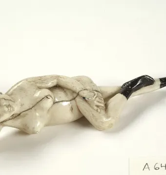 Doctor\'s Lady ivory figure reclining on its side, with dark hair, black-painted feet, and a small red hair adornment.
