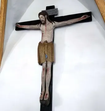 Enghausen Cross showing a painted wooden crucifix with Christ on a dark cross and a plaque above his head.