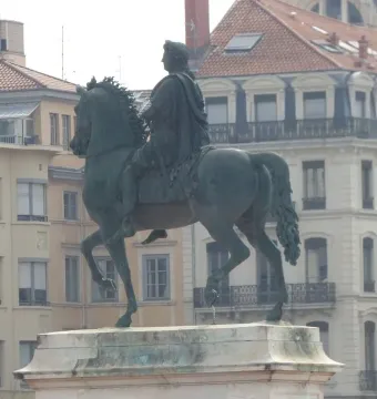 Louis XIV equestrian statue on a stone pedestal in Place Bellecour, with city buildings in the background.