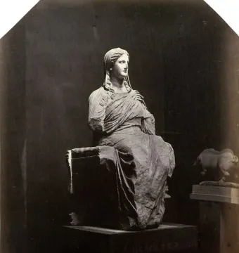 Demeter of Knidos, a draped seated statue with broken arms, photographed against a dark background.