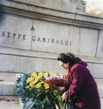A woman arranges a floral wreath at the base of the Garibaldi monument in Rome.