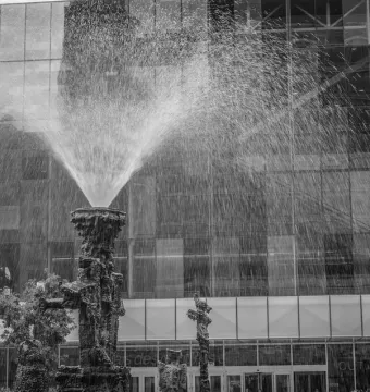 La Joute fountain sculpture spraying water in front of a modern glass building