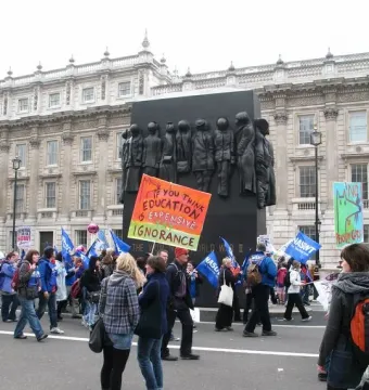 Monument to the Women of World War II partially covered by a protest banner in Whitehall, London.