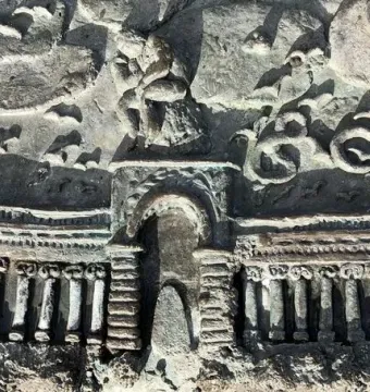 Close-up of the San Francisco Fountain relief sculpture with an arched colonnade, flanking towers, clouds, and a seated figure.