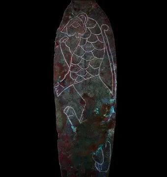 Spear of Lugal with an oxidized metal surface and a white line drawing of a feline creature etched on it.