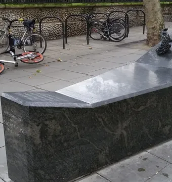 A Conversation with Oscar Wilde granite monument with a bronze bust holding a cigarette.