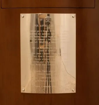 Polished metal plaque on the Gioiello di Vicenza, mounted on a dark curved wooden base with engraved text and a small emblem.