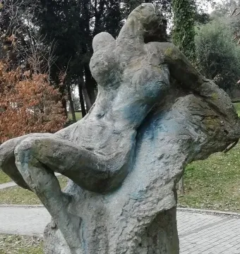 Güzel İstanbul, a weathered gray stone sculpture of a reclining figure on a stone base outdoors.