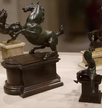 Dark bronze rearing horse sculptures with a small bronze mounted warrior figure on a pedestal in front.
