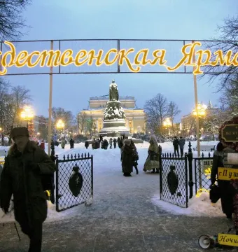 Catherine II Monument in a snowy square with people walking nearby at dusk.