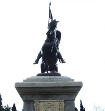El Cid sculpture of a rider on a rearing horse atop a tiered stone pedestal.