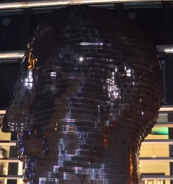 The Head of Franz Kafka sculpture in Prague, a large dark metallic head made of reflective horizontal panels.