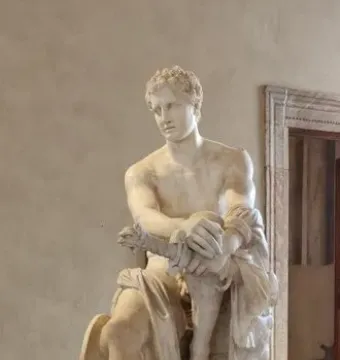 Ludovisi Ares seated in white marble, with a small winged child at his leg and a shield beside him.