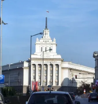 The Statue of Sofia on a tall dark column against a clear blue sky, with a streetlight in front.