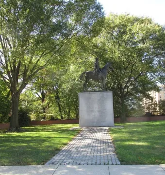 Bernardo de Gálvez equestrian bronze statue on a tall stone pedestal in a tree-lined park