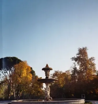 Fountain of the Artichoke standing in a paved plaza with autumn trees around it.