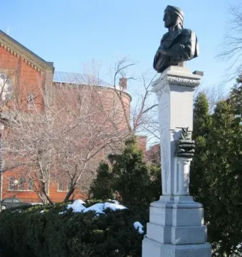 La mort de Dante monument with a dark bust on a tall stone pillar in a snowy park