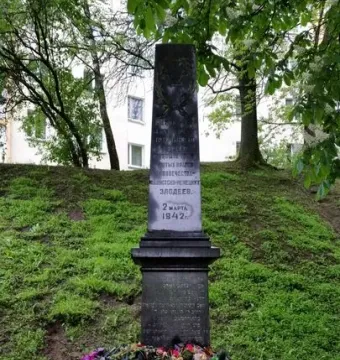 The Pit monument on a grassy mound with wreaths and flowers at its base.