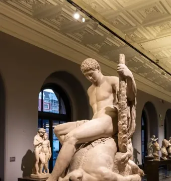 Theseus and the Minotaur marble sculpture showing a nude man seated over a defeated bull-headed creature