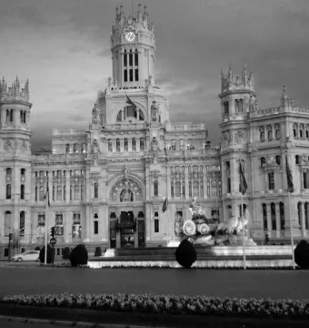The Cibeles Fountain with a classical figure in a chariot drawn by lions in front of a grand building.