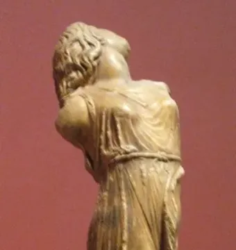 Dancing Maenad sculpture seen from behind, with the figure’s head tilted sharply upward and draped robes falling to the waist.