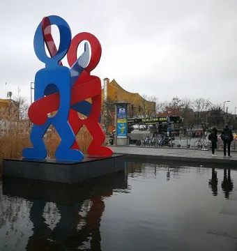 Keith Haring\'s The Boxers sculpture with two brightly colored figures standing in a shallow pool at Potsdamer Platz, Berlin.