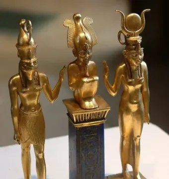 Osorkon II Triad with three figures on a rectangular base, including a central figure on a blue pedestal flanked by two standing figures.