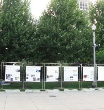Informational posters about Burnham Pavilions displayed on metal frames along a paved park walkway.