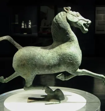 Flying Horse of Gansu bronze horse sculpture balanced on one hoof atop a bird on a display stand