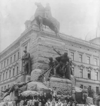 Crowd gathered in front of the Grunwald Monument, with an equestrian statue and bronze warrior figures on the pedestal.