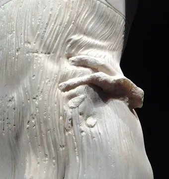 Close-up of the Motya Charioteer showing a marble hand against finely carved draped folds.