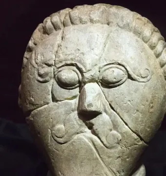Mšecké Žehrovice Head, a carved stone head with stylized eyes, a prominent nose, and patterned hair and cheek details.
