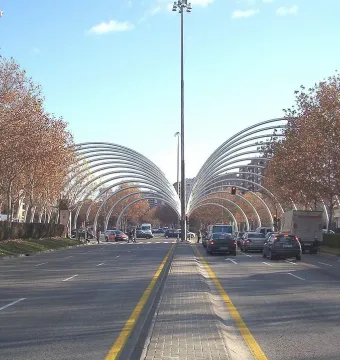 Puerta de la Ilustración spans a Madrid avenue with curved metallic arches over the road and a tall central light pole.