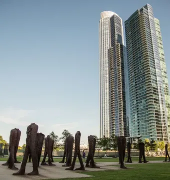 Agora sculptures on a green lawn with Chicago skyscrapers in the background.