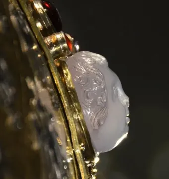 Close-up of Charlemagne\'s bust reliquary showing a carved light-colored cameo face set in ornate gold metalwork with red jewels.