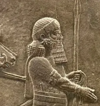 Detail of the Lion Hunt of Ashurbanipal relief showing a bearded figure in profile with a spear and ornate robe.