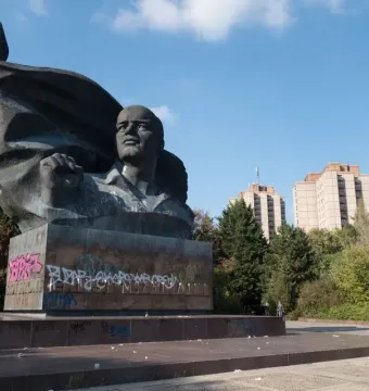 Ernst Thälmann Memorial bronze bust on a graffiti-covered pedestal with a flag-like sculpture behind it.