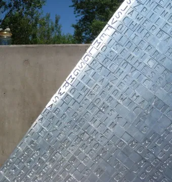 Hailfingen-Tailfingen Memorial panel with engraved names beside a concrete wall and a small jar of stones