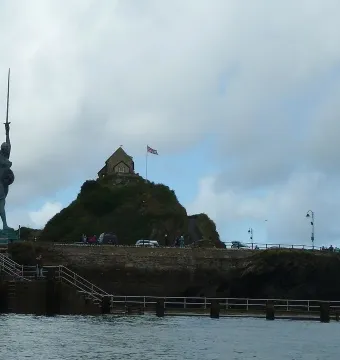 Verity, a dark bronze statue, stands on a stone pier and raises a sword toward the sky.