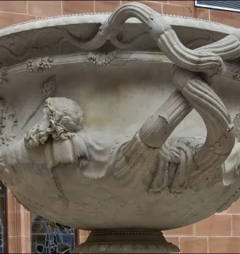 Side view of the Warwick Vase, showing its ornate carved heads and intertwined vine-like handles.