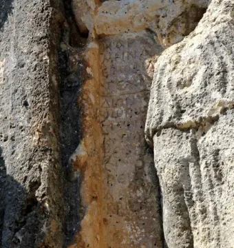 Ancient inscription carved into a weathered rock face beside the Athena relief.
