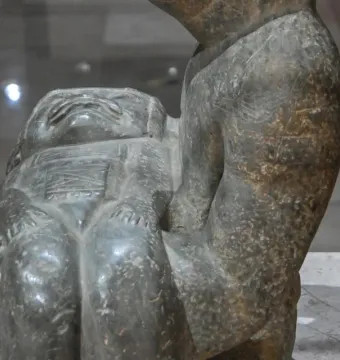 Las Limas Figurine showing a stone figure cradling a smaller carved figure with a stylized face and closed eyes.