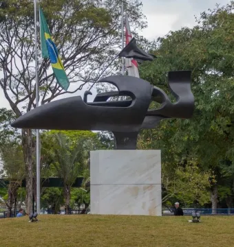 Ayrton Senna Monument on a grassy mound with a dark abstract race car-like sculpture and Brazilian flags behind it.