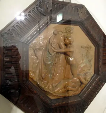 Creation of Eve terracotta relief in a dark octagonal frame, showing a draped figure embracing a nude figure above a prostrate figure.